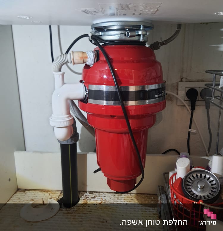 מטחנת אשפה אדומה מותקנת מתחת לכיור במטבח